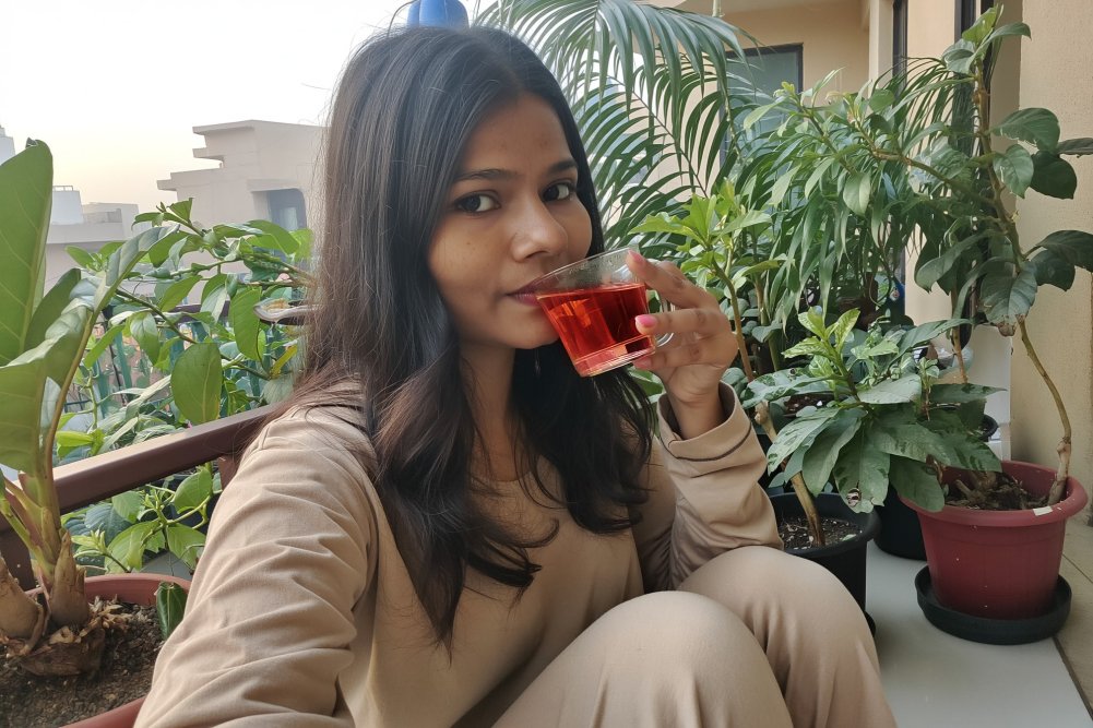 a girl sipping hibiscus tea in her terrace garden
